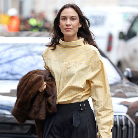 Alexa Chung wears a butter yellow skirt with a knee-length skirt and brown heels.