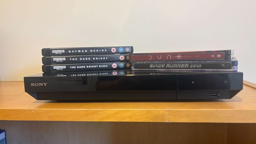 A Sony Blu-ray player sitting on a shelf with the Dark Knight trilogy, Blade Runner 2049 and Dune Part Two Blu-ray cases sitting on top