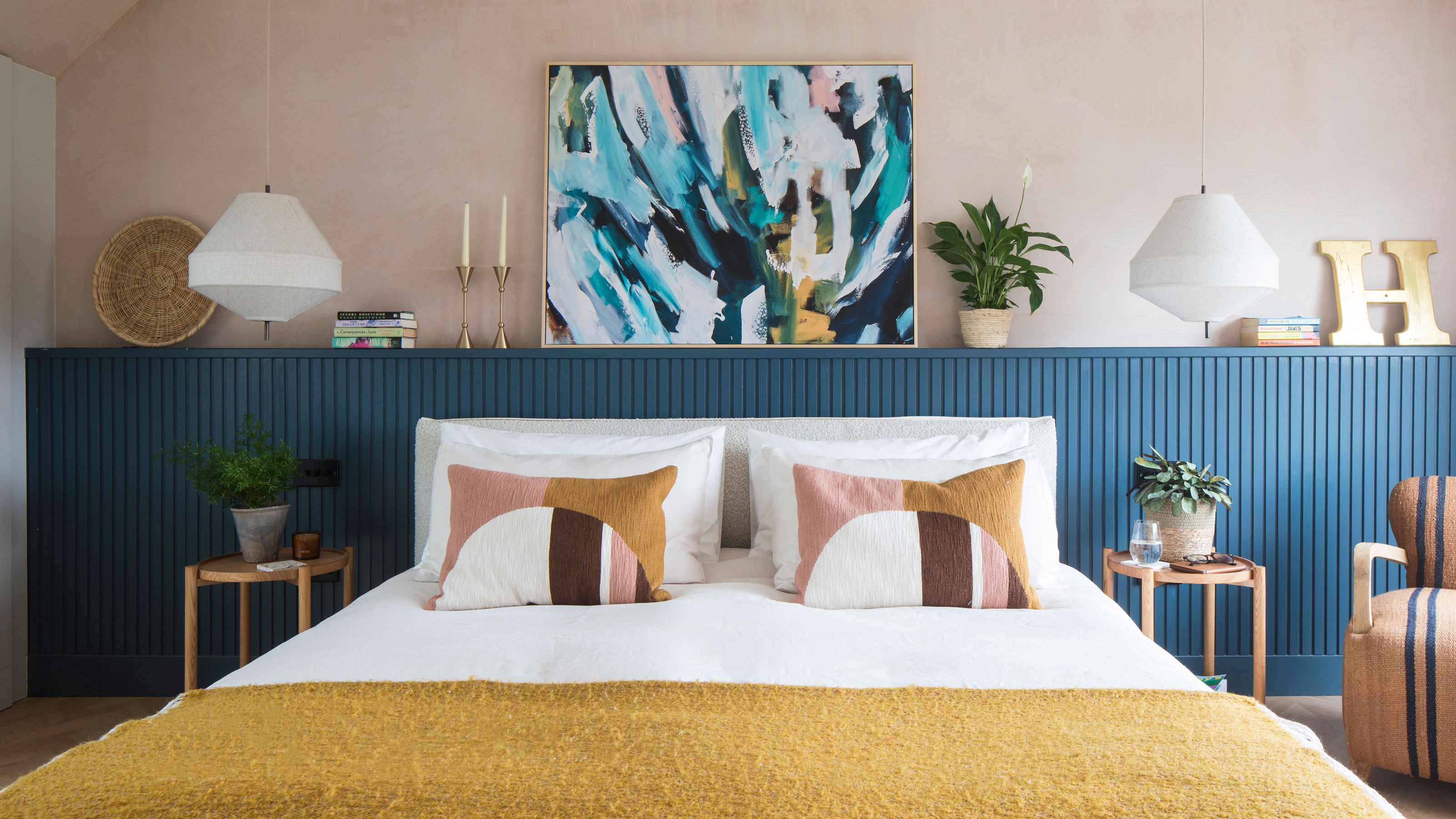 Pink bedroom with blue headboard and white double bed with throw cushions
