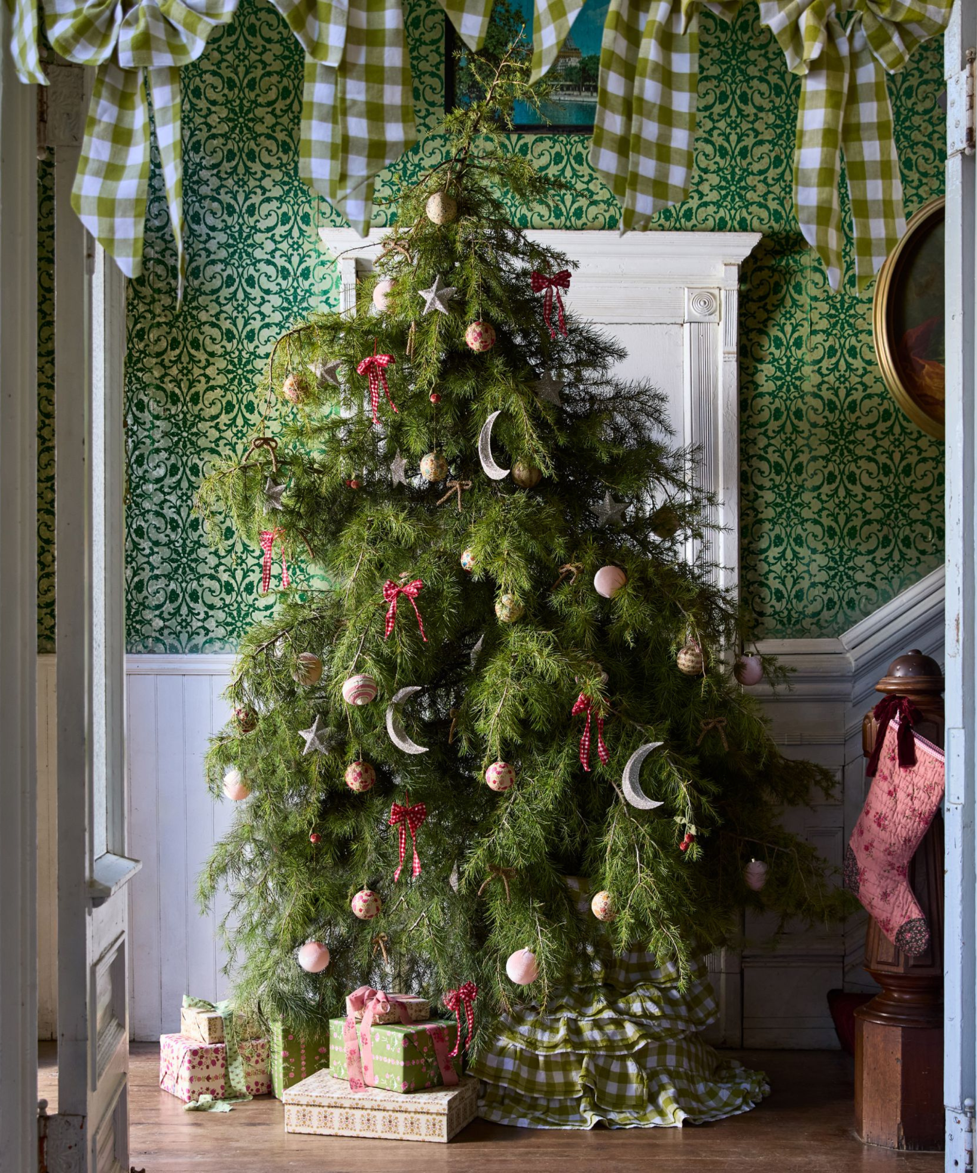 a green Christmas tree decorated with ornaments with presents underneath