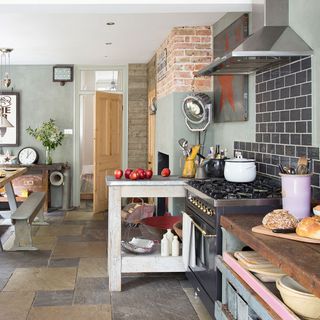 vintage kitchen with black gas stove, storage table and stone flooring