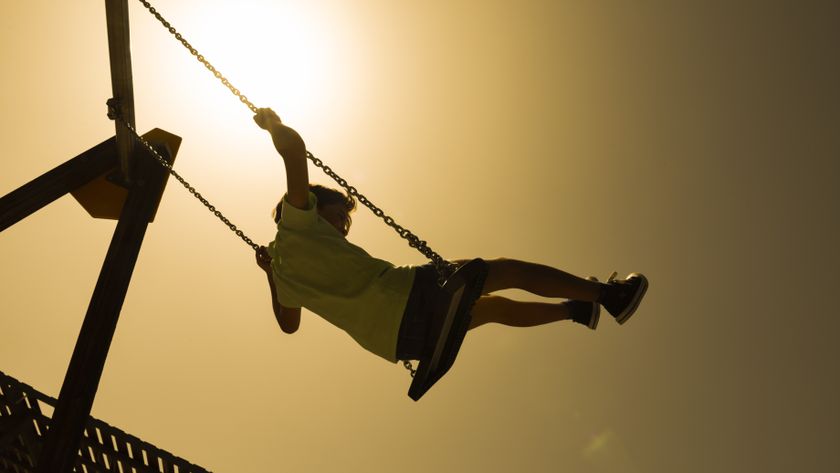 Photo of a young girl on a swing set under a cloudless and very bright sky