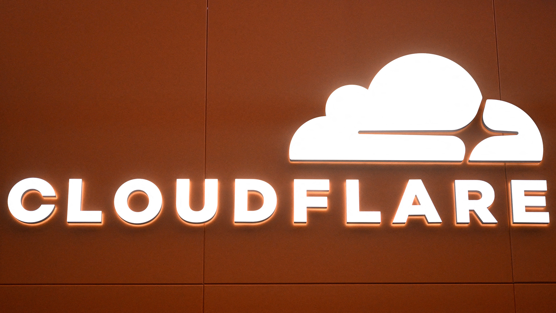 Cloudflare logo and branding illuminated in white coloring against an orange background at the 2026 World Economic Forum (WEF) in Davos.
