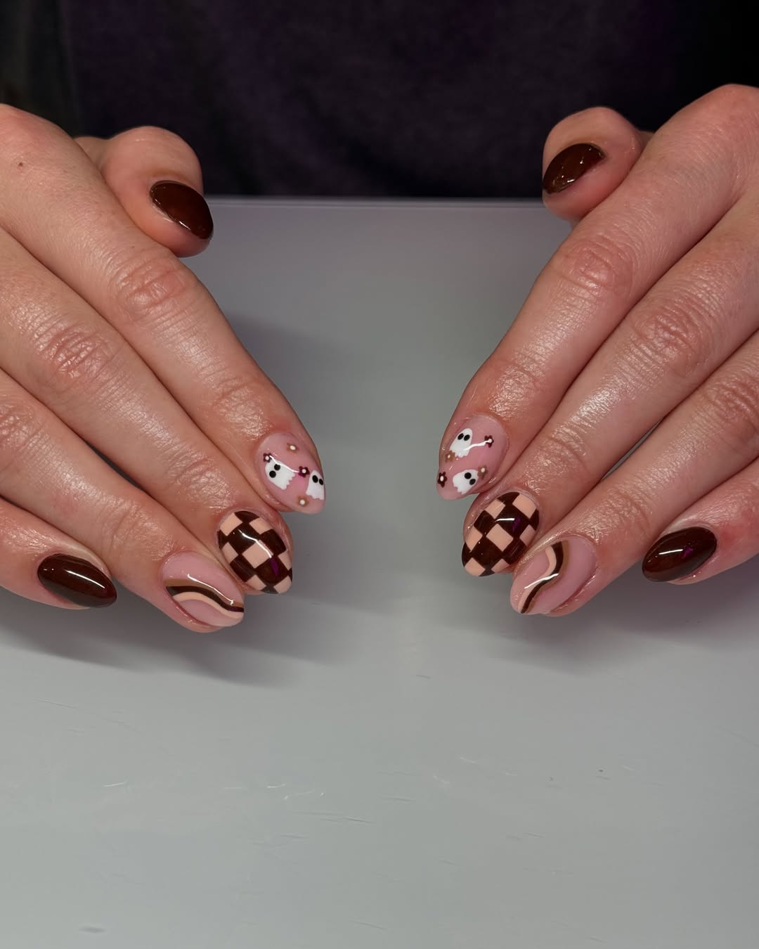 a manicure featuring multiple shades of brown and swirl and checker designs