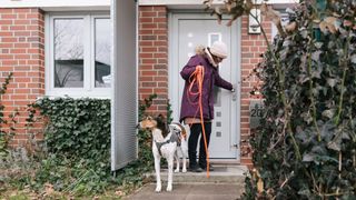 Woman leaving her house with a dog on long leash