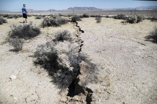 An onlooker views newly ruptured ground after a 7.1-magnitude earthquake struck on July 6, 2019, near Ridgecrest, California.