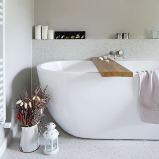 Contemporary white bath with ledge shelf and white jug and lamp