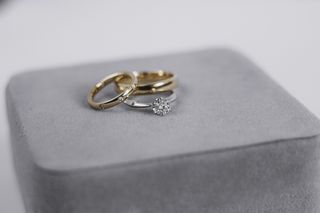A silver diamond ring along with two rose gold rings, on a grey velvet stand.