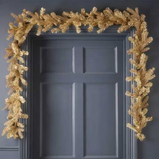 Gold garland hung over a doorway in a dark blue hallway to show how to style a hallway