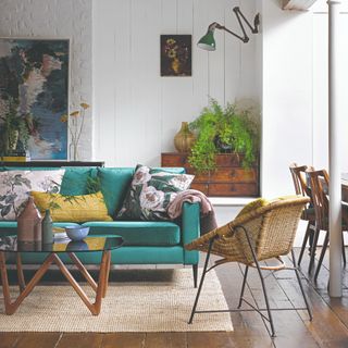 An emerald green velvet sofa on a neutral-coloured rug with a glass coffee table