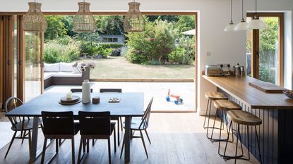 Black dining table in front of small kitchen with various appliances