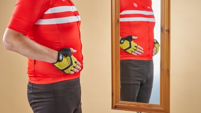 A male cyclist looking at his body in a mirror 