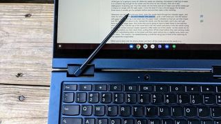 Lenovo ThinkPad C13 Yoga Chromebook laying flat on a wooden table with a stylus on top of its display.