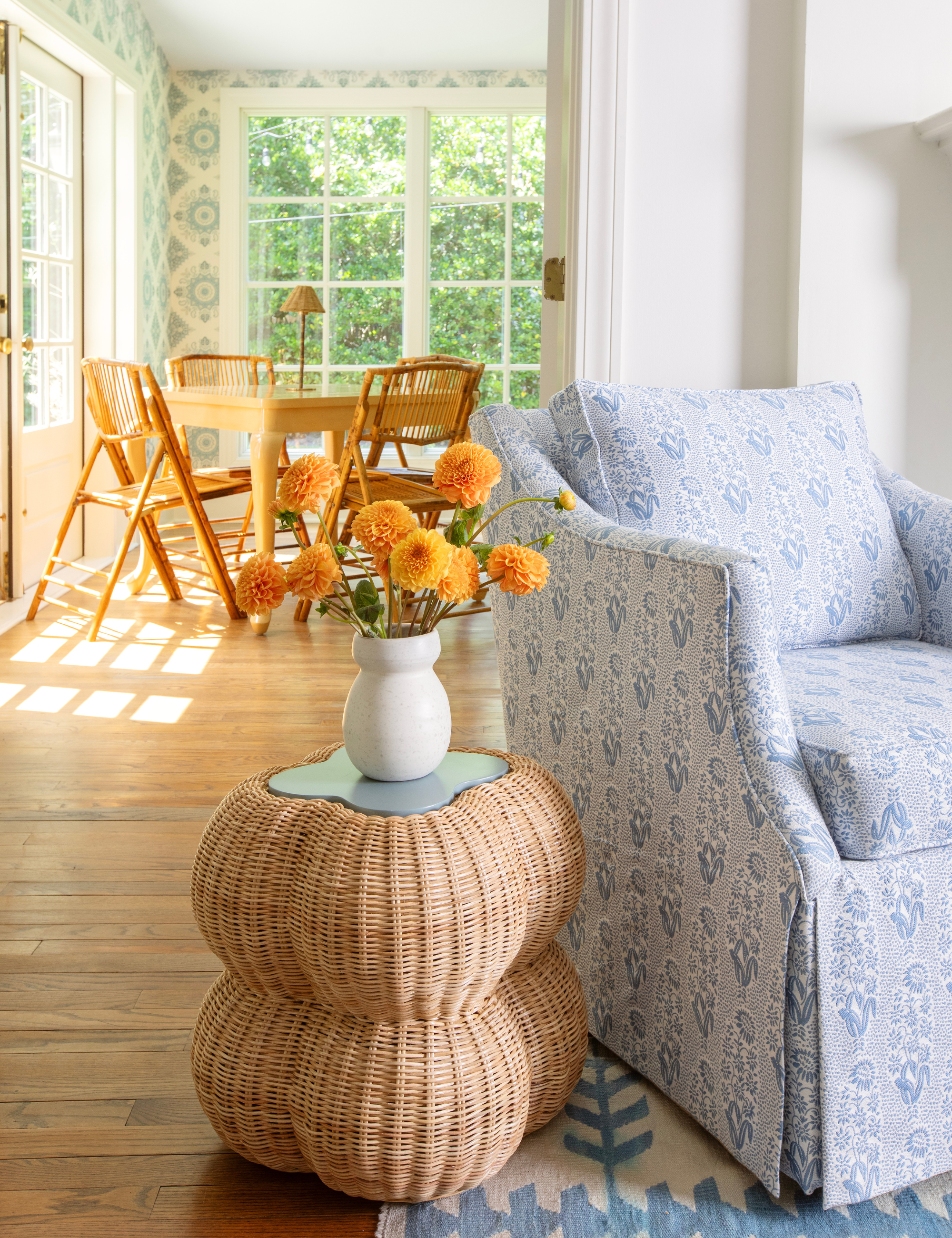Blue patterned swivel armchair styled alongside a sculptural rattan side table topped with marigolds