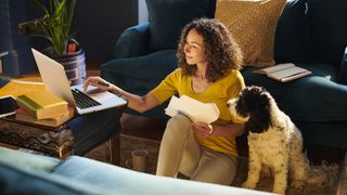 lady looking at computer and notepads with dog beside her