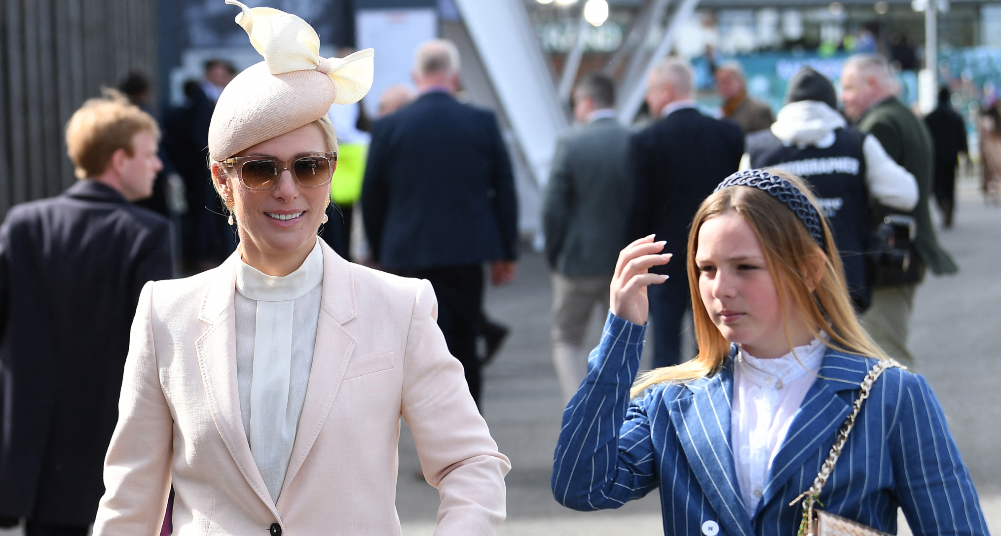 Zara Tindall wearing a pink suit walking next to Mia Tindall in a blue striped suit