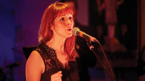 Amy Birks from The Beatrix Players singing into a microphone on stage