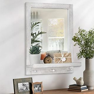 A rustic white wooden wall mirror with three hanging hooks and a small shelf 