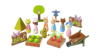 A wooden painted Peter Rabbit toys set which include characters like Peter Rabbit and Jemima Puddleduck plus wooden trees, a wheelbarrow and vegetable patches.