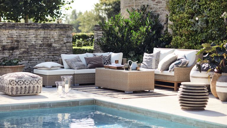One of the best rattan garden furniture sets on a paved courtyard by the side of a pool