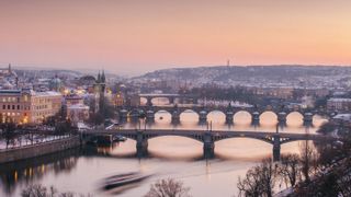 The skyline of Prague including the Charles Bridge at sunset with a pink sky