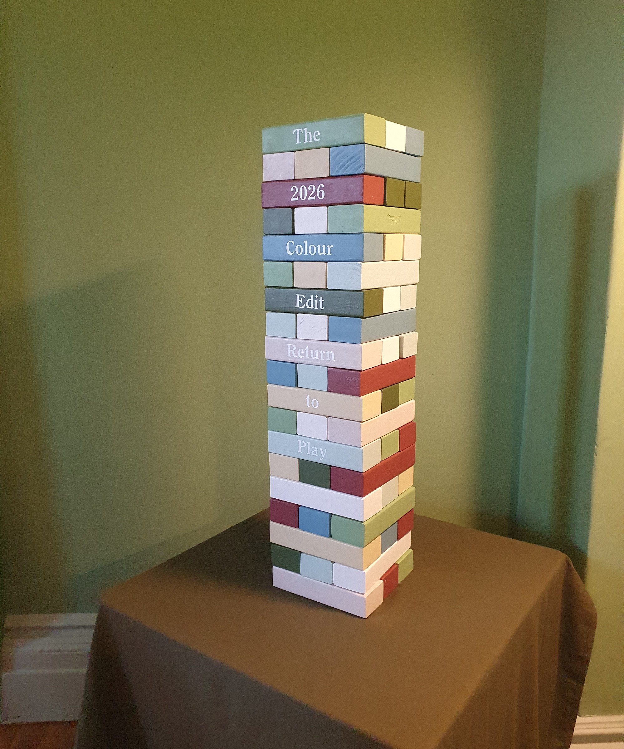 A jenga tower with pieces painted in Lick&#039;s colour edit 2026 set against a wall painted in Green 18.