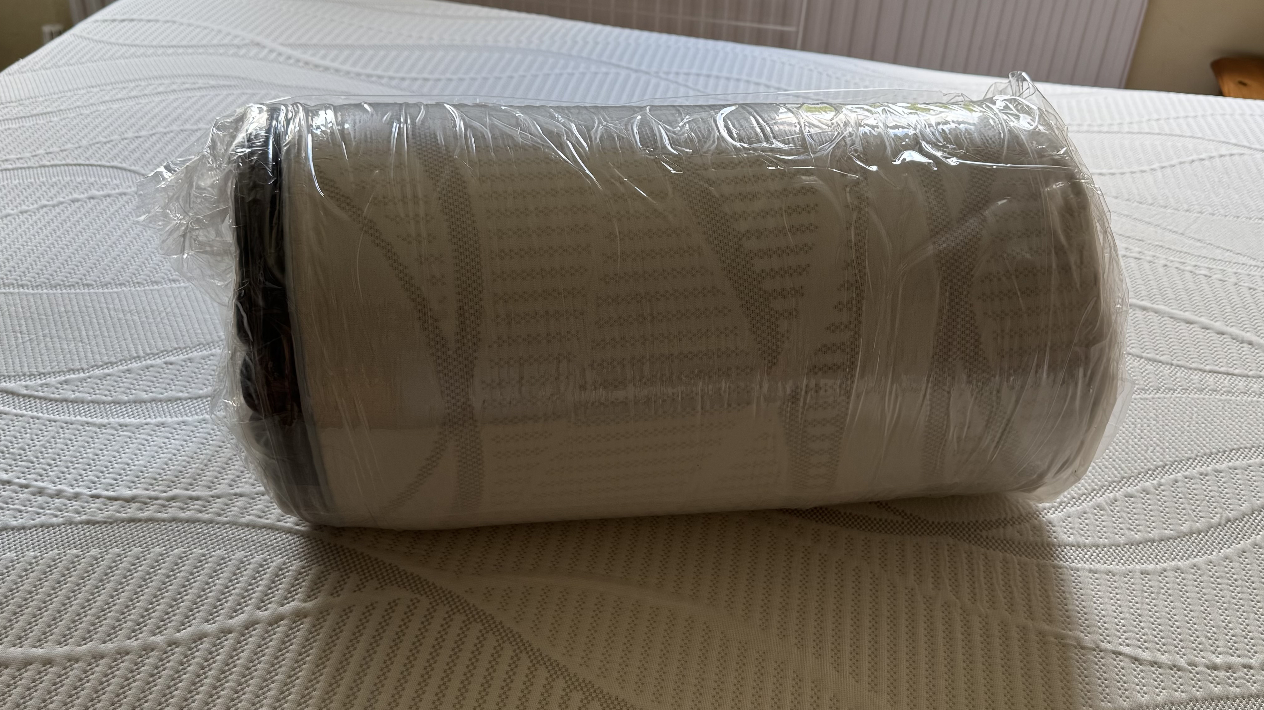 The Nectar mattress topper unboxed but still compressed and wrapped in plastic.