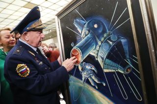 Retired cosmonaut Alexei Leonov stands with his painting of his historic first-ever spacewalk, during which he spent about 12 minutes outside the confines of the Voskhod 2 vehicle in 1965.