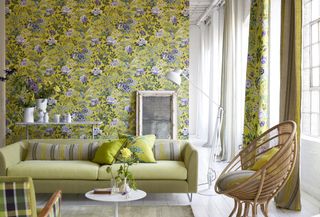 living room with yellow floral wallpaper, lime green couch, white painted floor, white floor lamp, wicker chair, white accessories