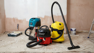 Three of the best vacuum cleaners for builders dust on a dust sheet with a half painted wall in the background