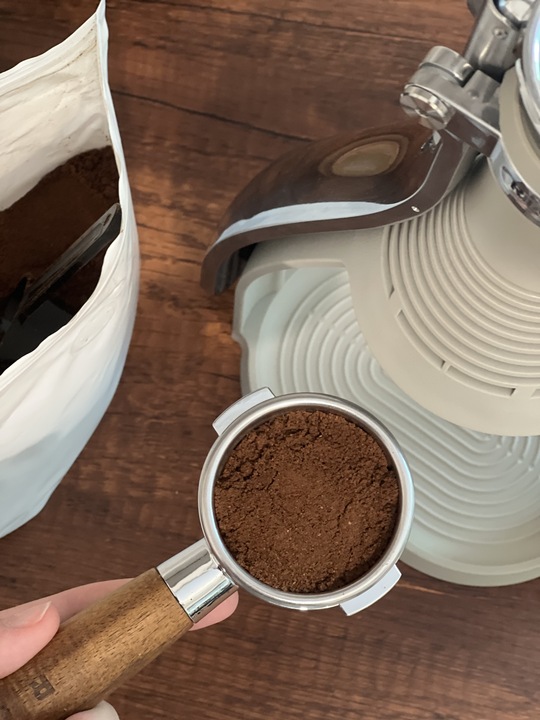Close-up image of a coffee handle with coffee grounds in it.