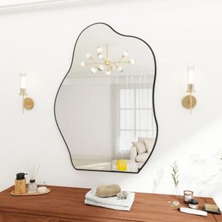 A black-framed wavy mirror hung above a console table