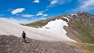 A hiker high on a ridge above a scree field