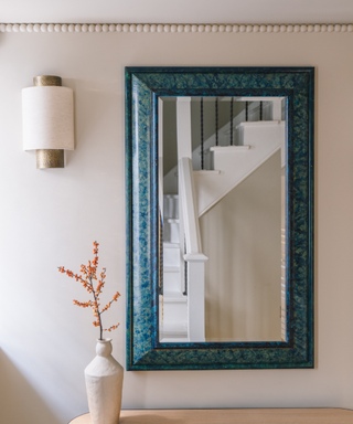 hallway with beaded plaster border, wall light, mirror and console with vase