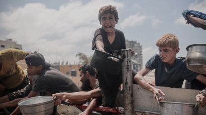 A child extends his pot amid food shortages in Gaza