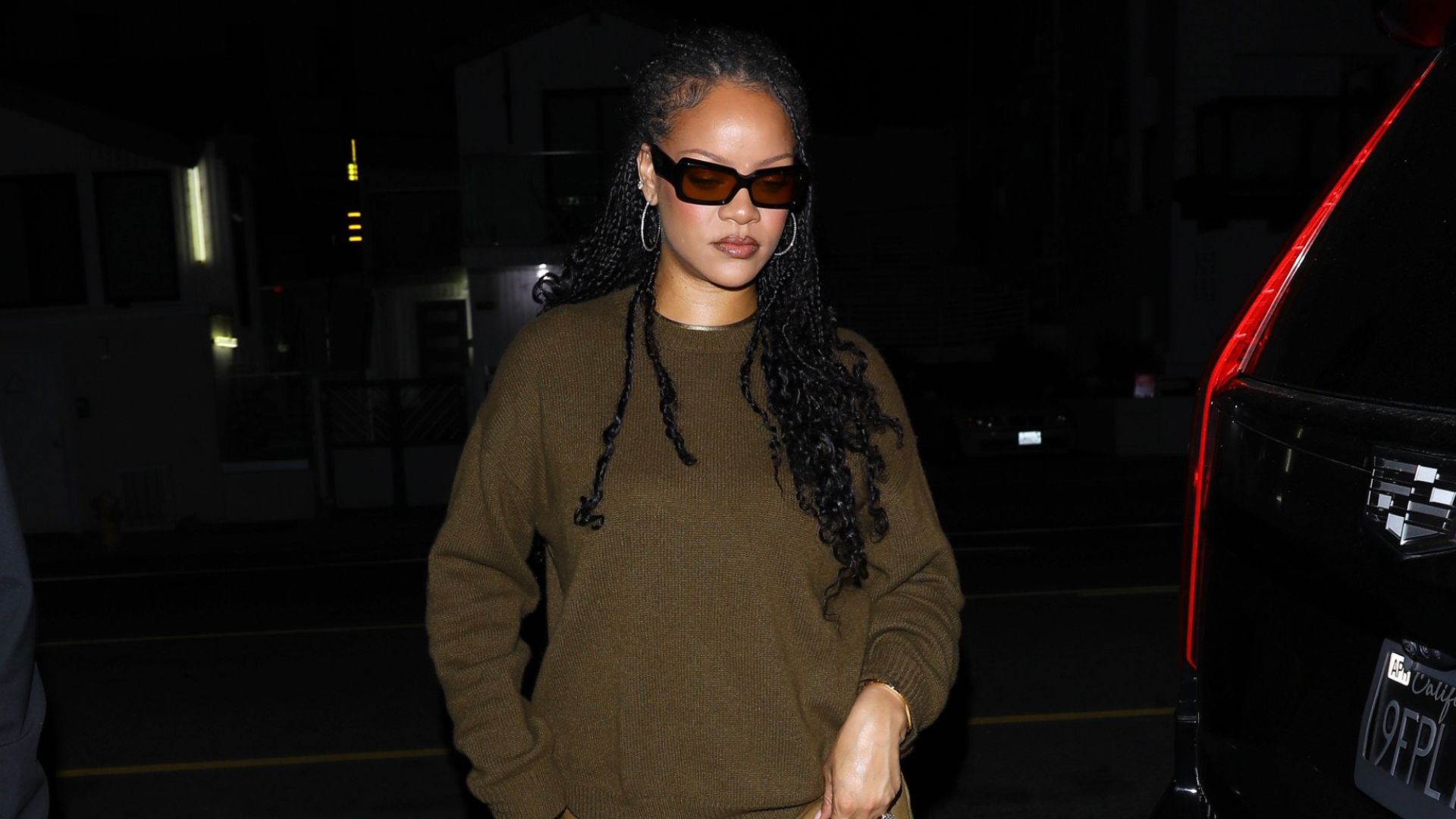 Rihanna steps out at night wearing a khaki jumper with khaki jeans and black ballet flats.