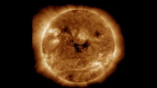 The sun appears to have a smiling face made from dark regions called coronal holes.