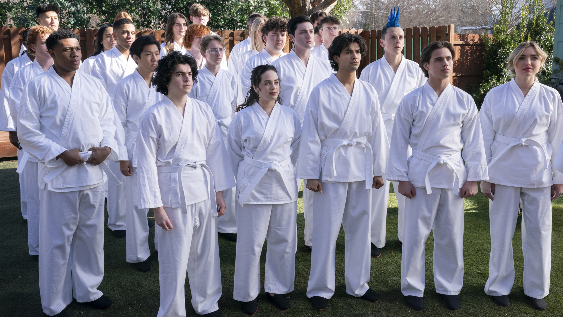 A group of karate students stand close together in a garden in Cobra Kai season 6