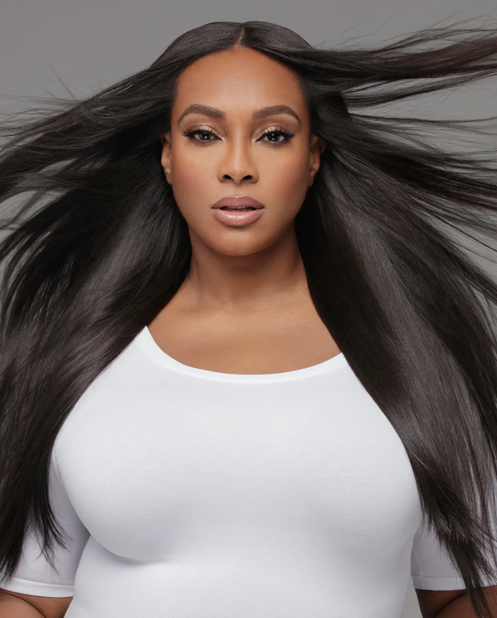 a black woman in a white top with long windswept black hair