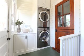 A small laundry room with stacked machines and full-height cabinetry