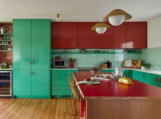 kitchen with green base units and red wall cabinets and red-topped island