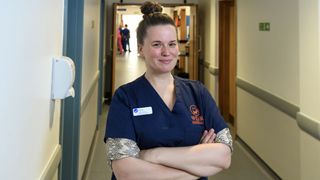 Vet Anna Cronin in scrubs stands in a corridor in 24/7 Pet Hospital
