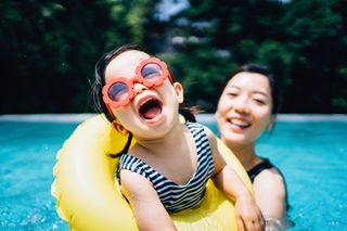 Mother and daughter playing in swimming pool