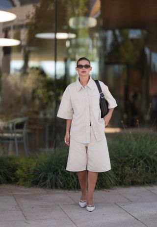 woman wearing cream bermuda shorts with cream collared top