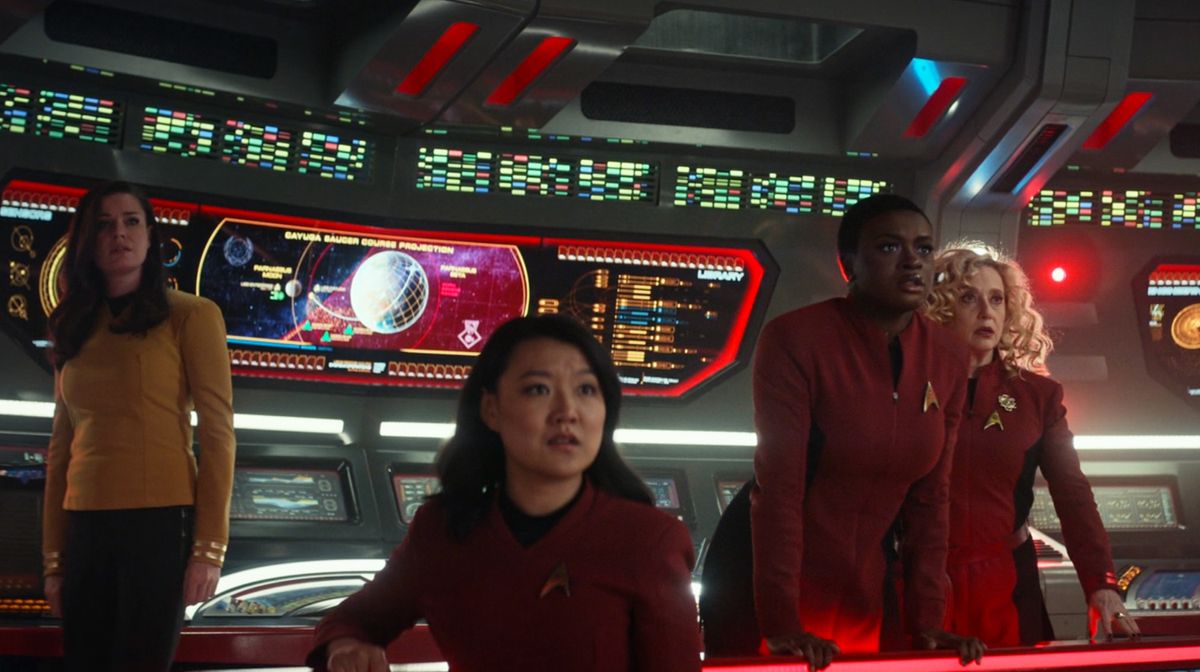 four women on a starship bridge with illuminated displays behind them