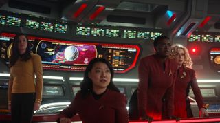 four women on a starship bridge with illuminated displays behind them