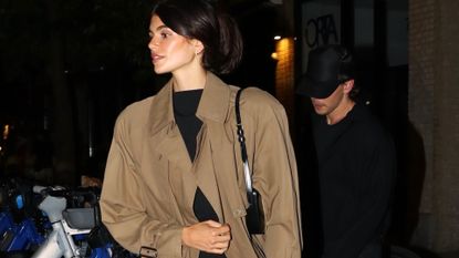 kaia gerber embraces fall trends in knee-high boots and a trench coat