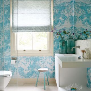 bathroom with printed blue walls and tiled flooring