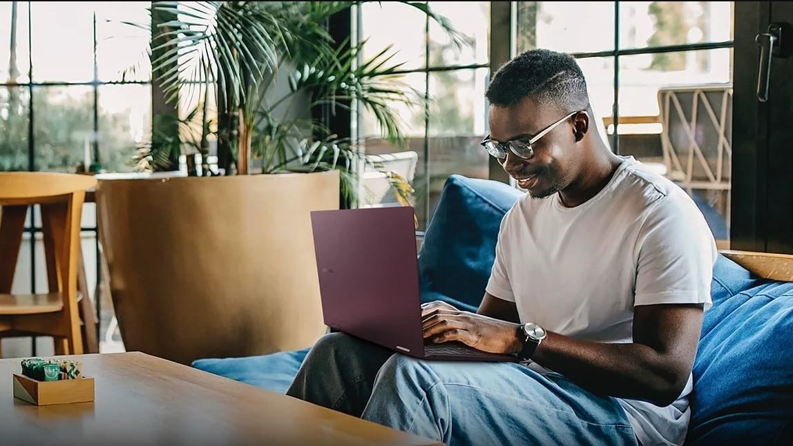 Person on couch using Galaxy Book laptop