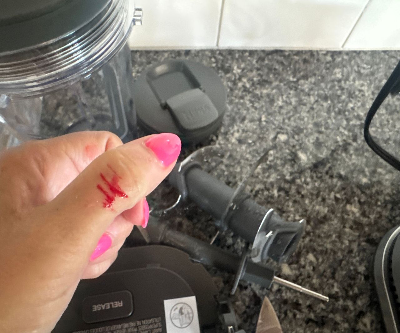 A close up of a bleeding cut on a thumb after catching the skin on one of the sharp food processor blades.